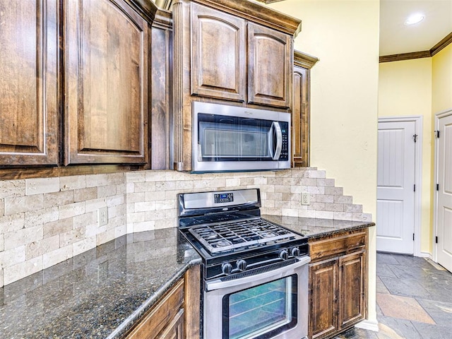 2311 Washita Trl, Edmond, OK 73003 - kitchen with stainless steel appliances, crown molding, decorative backsplash, stone tile floors, and dark stone countertops