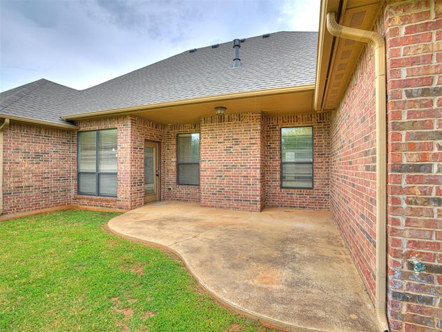 2311 Washita Trl, Edmond, OK 73003 - back of property featuring roof with shingles, brick siding, a patio, and a lawn