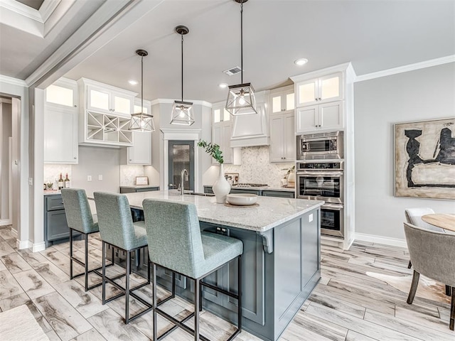 15913 Windrush Pl, Edmond, OK 73013 - kitchen with ornamental molding, appliances with stainless steel finishes, decorative backsplash, white cabinetry, and an island with sink