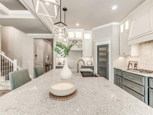 15913 Windrush Pl, Edmond, OK 73013 - kitchen with stainless steel gas cooktop, backsplash, custom range hood, light stone counters, and crown molding