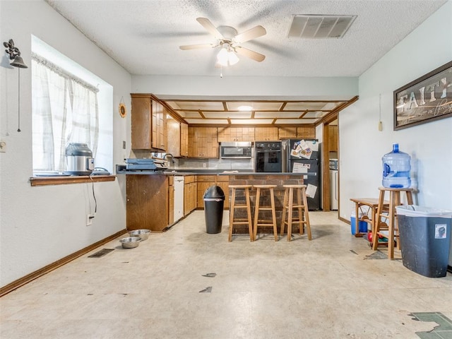 200 S Morgan Dr, Moore, OK 73160 - kitchen featuring stainless steel appliances, dark countertops, brown cabinetry, a ceiling fan, and a textured ceiling