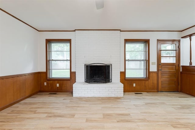 320 E 13th St, Edmond, OK 73034 - unfurnished living room featuring wainscoting, light wood-style flooring, ornamental molding, a brick fireplace, and wooden walls