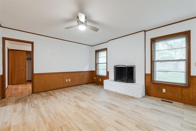 320 E 13th St, Edmond, OK 73034 - unfurnished living room featuring wainscoting, crown molding, light wood-style floors, ceiling fan, and a brick fireplace