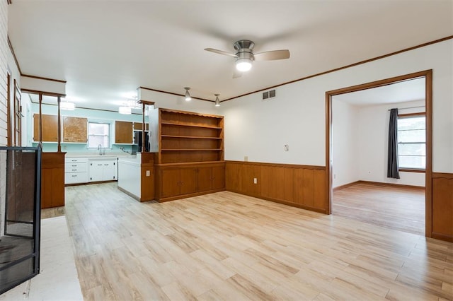 320 E 13th St, Edmond, OK 73034 - unfurnished living room featuring wainscoting, a ceiling fan, light wood-style flooring, and crown molding