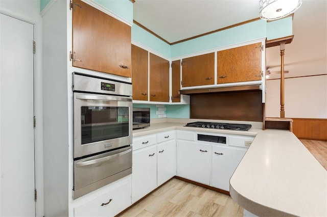 320 E 13th St, Edmond, OK 73034 - kitchen featuring appliances with stainless steel finishes, a warming drawer, light wood-style flooring, light countertops, and under cabinet range hood
