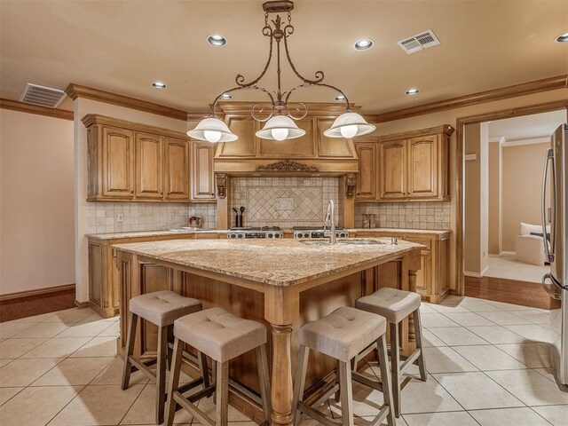 325 NW 146th St, Edmond, OK 73013 - kitchen featuring ornamental molding, light tile patterned floors, an island with sink, light stone counters, and a breakfast bar