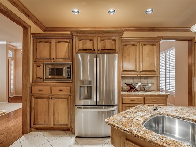 325 NW 146th St, Edmond, OK 73013 - kitchen featuring stainless steel appliances, crown molding, light stone countertops, tasteful backsplash, and brown cabinetry