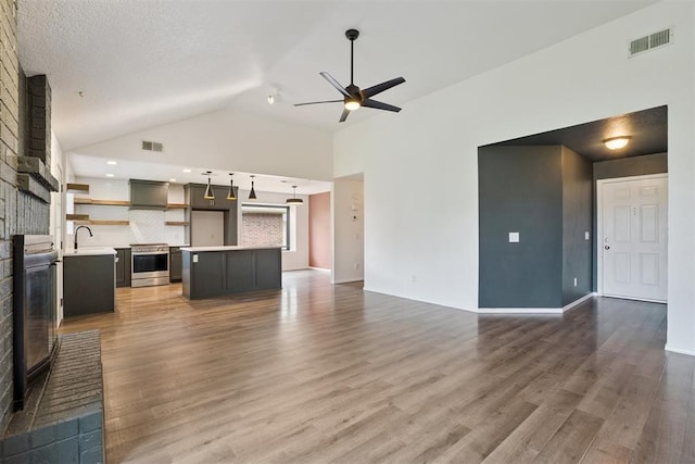 1729 Dena Dr, Edmond, OK 73003 - unfurnished living room featuring a brick fireplace, ceiling fan, wood finished floors, and vaulted ceiling