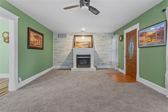 625 N Broadway St, Hydro, OK 73048 - unfurnished living room featuring carpet, a fireplace with raised hearth, ceiling fan, and an accent wall