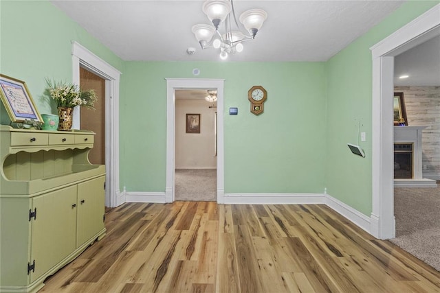 625 N Broadway St, Hydro, OK 73048 - unfurnished dining area with light wood-style flooring, a chandelier, and a fireplace with raised hearth