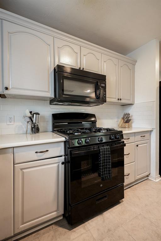 1701 Andover Ct, The Village, OK 73120 - kitchen with black appliances, backsplash, light countertops, light tile patterned floors, and white cabinets