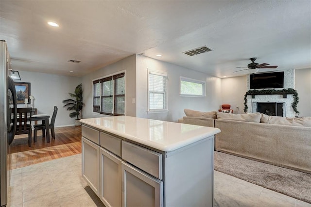 1701 Andover Ct, The Village, OK 73120 - kitchen with a kitchen island, open floor plan, ceiling fan, a fireplace, and gray cabinetry