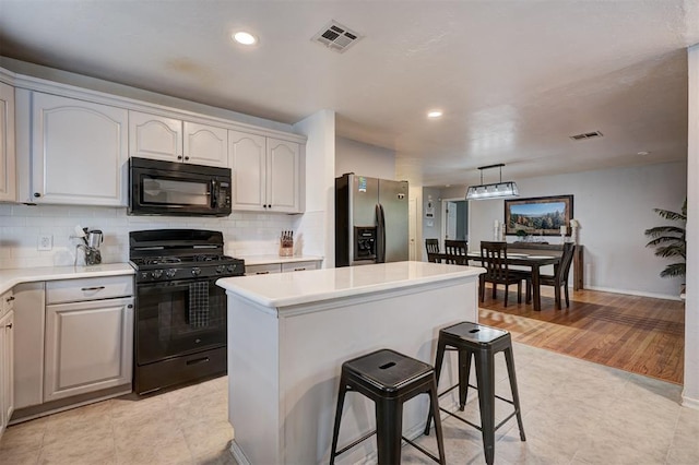 1701 Andover Ct, The Village, OK 73120 - kitchen featuring black appliances, decorative backsplash, light countertops, recessed lighting, and a kitchen island