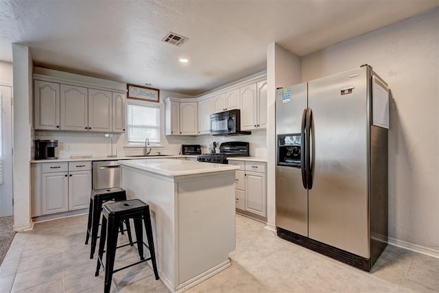 1701 Andover Ct, The Village, OK 73120 - kitchen with black appliances, a center island, a breakfast bar area, and light countertops