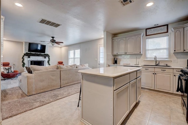1701 Andover Ct, The Village, OK 73120 - kitchen with a kitchen island, open floor plan, a large fireplace, gray cabinets, and decorative backsplash