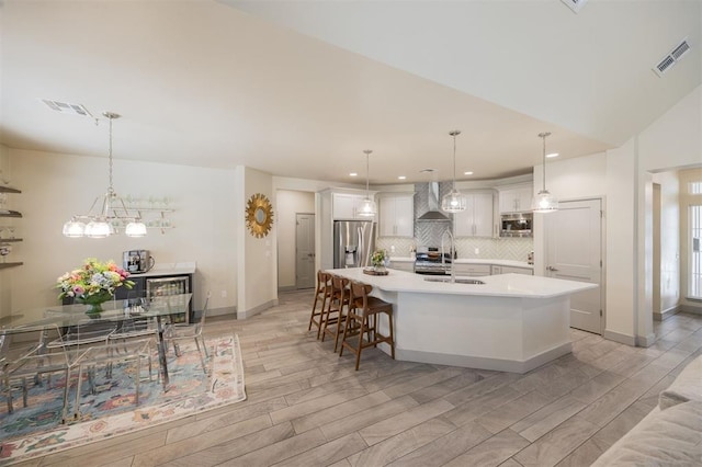 5521 N Miller Ave, Oklahoma City, OK 73112 - kitchen with appliances with stainless steel finishes, wall chimney range hood, decorative backsplash, light wood-type flooring, and a spacious island