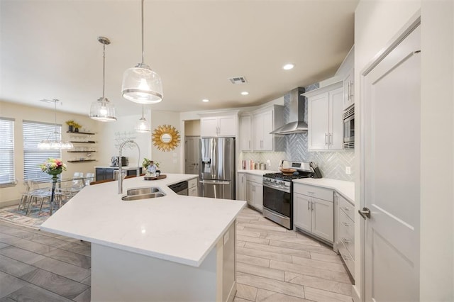 5521 N Miller Ave, Oklahoma City, OK 73112 - kitchen with appliances with stainless steel finishes, wall chimney range hood, backsplash, a kitchen island with sink, and wood tiled floors