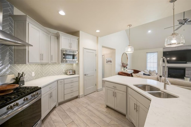5521 N Miller Ave, Oklahoma City, OK 73112 - kitchen featuring wall chimney range hood, stainless steel appliances, open floor plan, backsplash, and light countertops