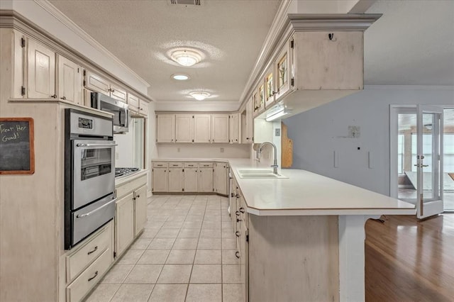 829 Arnold Ave, Moore, OK 73160 - kitchen with a warming drawer, appliances with stainless steel finishes, a peninsula, ornamental molding, and light countertops