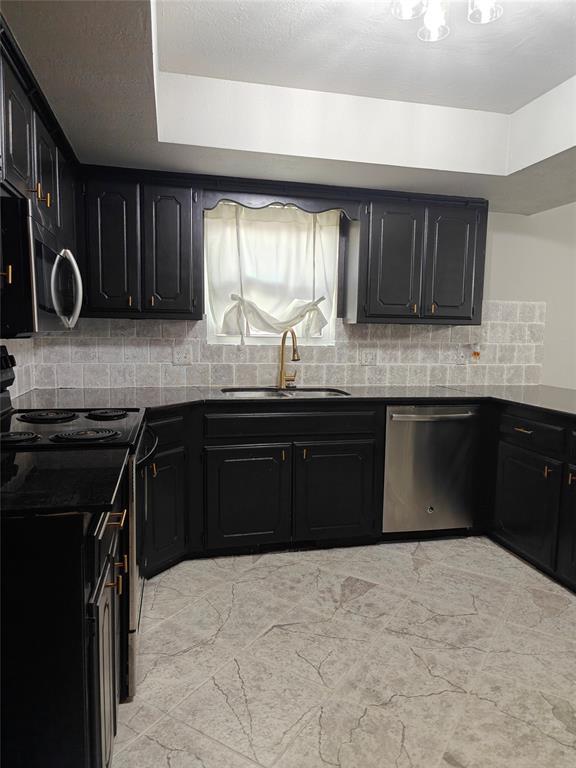 11208 NW 113th St, Yukon, OK 73099 - kitchen featuring appliances with stainless steel finishes, dark countertops, dark cabinetry, and backsplash