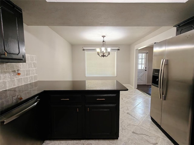 11208 NW 113th St, Yukon, OK 73099 - kitchen with stainless steel appliances, a peninsula, dark cabinets, a chandelier, and dark countertops