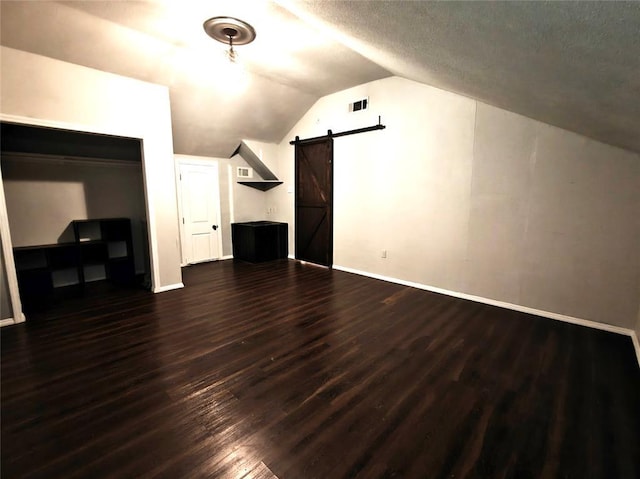 11208 NW 113th St, Yukon, OK 73099 - additional living space with a barn door, vaulted ceiling, dark wood-style flooring, and a textured ceiling