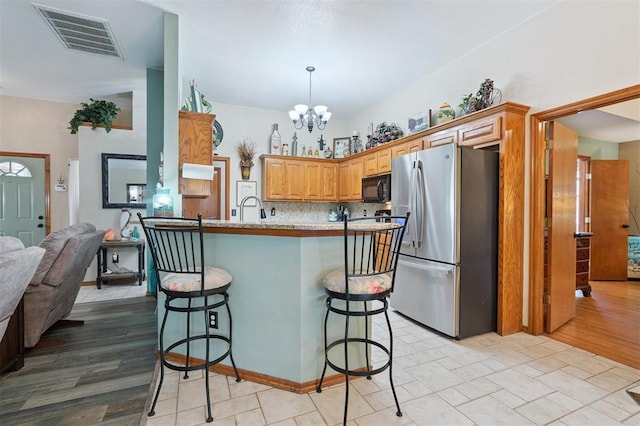 6005 SE 82nd Cir, Oklahoma City, OK 73135 - kitchen with black microwave, freestanding refrigerator, a kitchen breakfast bar, a chandelier, and light countertops