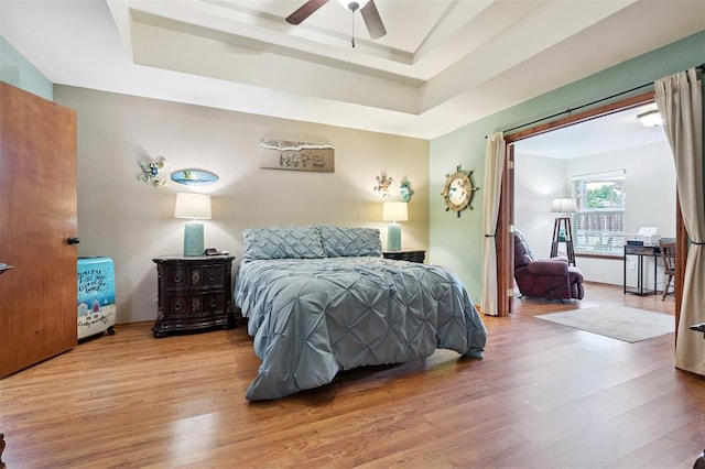 6005 SE 82nd Cir, Oklahoma City, OK 73135 - bedroom featuring wood finished floors, a tray ceiling, and a ceiling fan