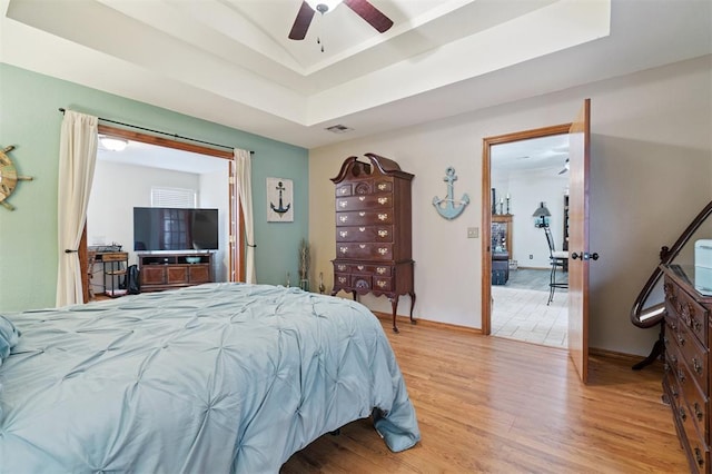6005 SE 82nd Cir, Oklahoma City, OK 73135 - bedroom with light wood-style floors, a tray ceiling, and ceiling fan