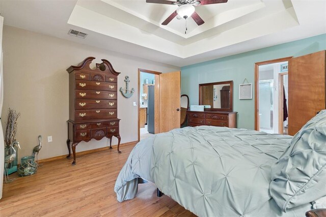 6005 SE 82nd Cir, Oklahoma City, OK 73135 - bedroom featuring a tray ceiling, wood finished floors, ensuite bath, and ceiling fan
