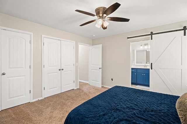 104 N Ramblin Oaks Dr, Moore, OK 73160 - bedroom featuring a barn door, light colored carpet, connected bathroom, ceiling fan, and a closet