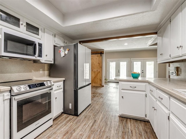 6708 Basswood Canyon Rd, Oklahoma City, OK 73162 - kitchen featuring appliances with stainless steel finishes, light countertops, a peninsula, and white cabinetry