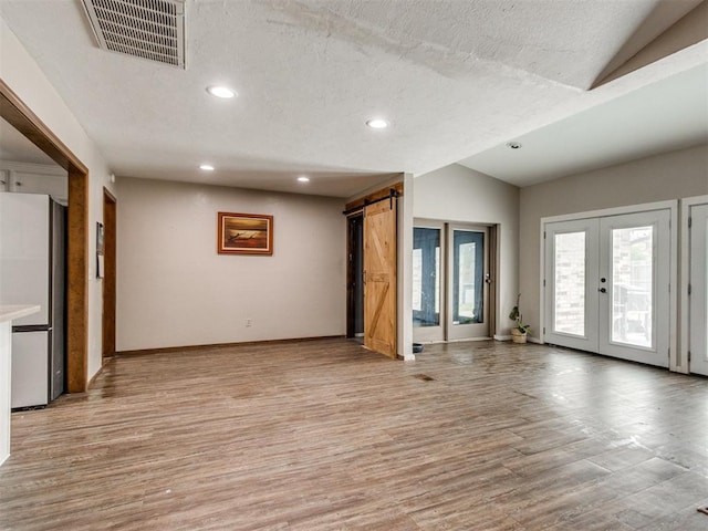 6708 Basswood Canyon Rd, Oklahoma City, OK 73162 - unfurnished living room featuring lofted ceiling, light wood finished floors, recessed lighting, french doors, and a barn door
