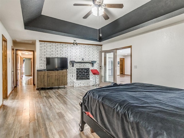 6708 Basswood Canyon Rd, Oklahoma City, OK 73162 - bedroom featuring a raised ceiling, wood finished floors, and a fireplace