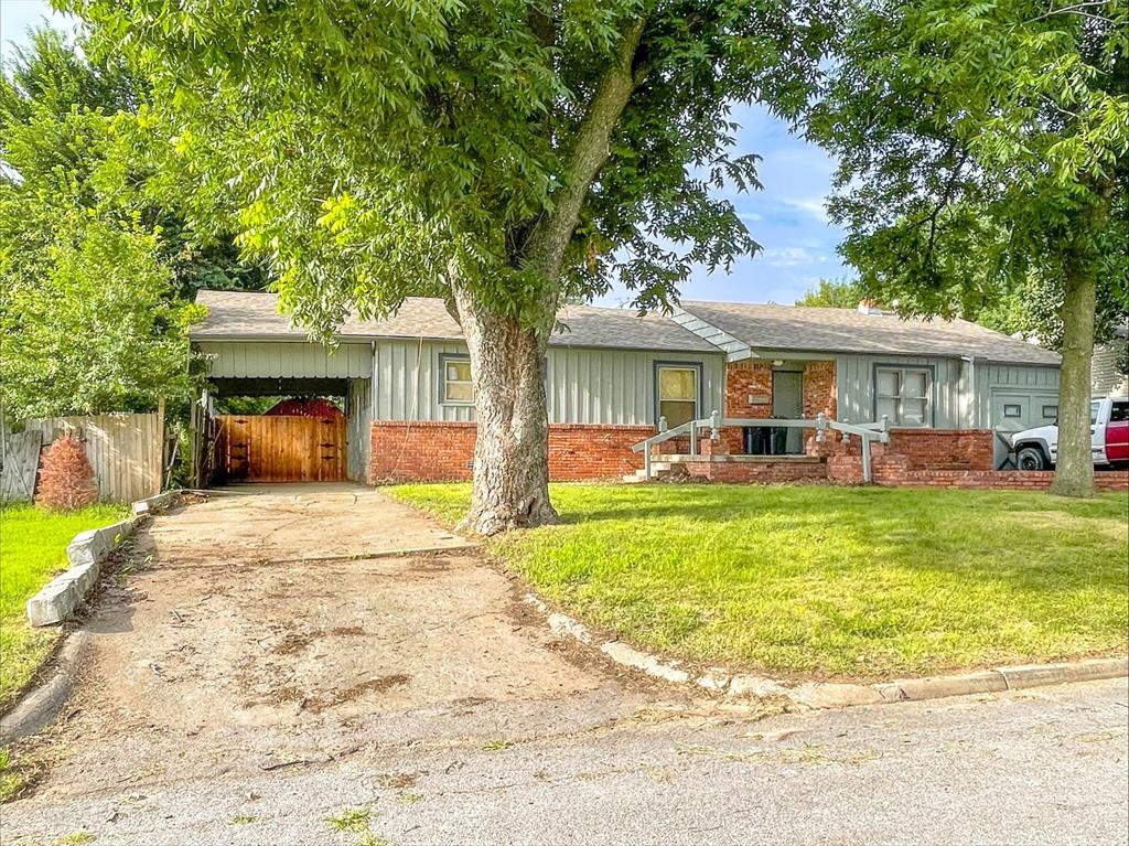6112 NW 49th St, Warr Acres, OK 73122 - ranch-style house with brick siding, driveway, roof with shingles, and an attached carport
