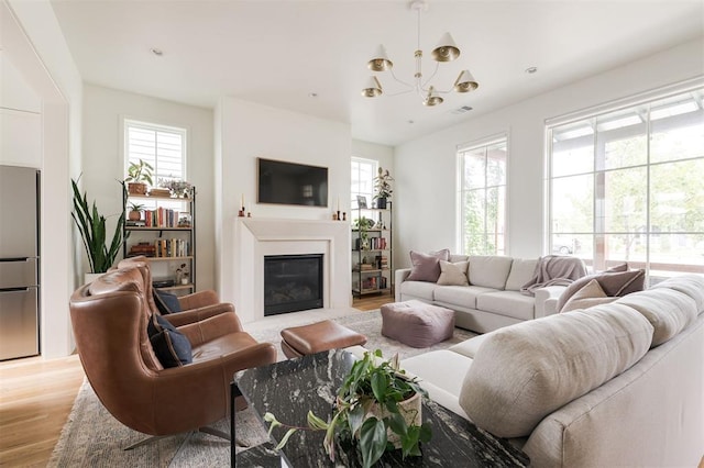 1900 Runway Blvd, Oklahoma City, OK 73108 - living area featuring light wood finished floors, a chandelier, and a fireplace with flush hearth