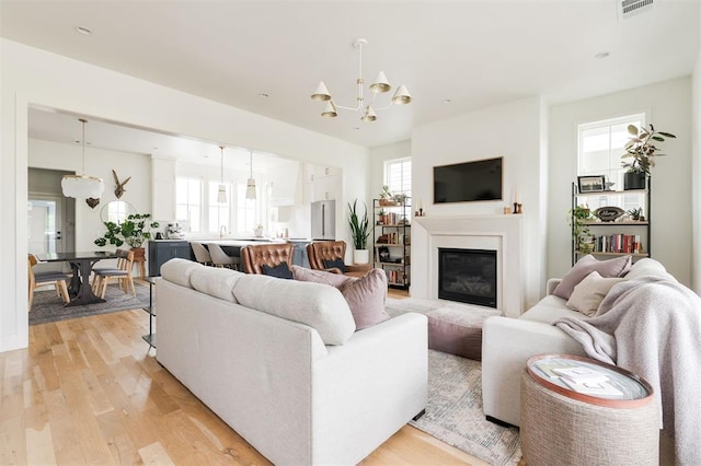 1900 Runway Blvd, Oklahoma City, OK 73108 - living room with a chandelier, light wood-style flooring, and a glass covered fireplace