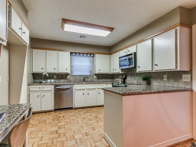 1221 Val Genes Rd, Edmond, OK 73003 - kitchen with stainless steel appliances, white cabinets, tasteful backsplash, and a textured ceiling
