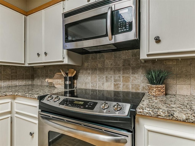 1221 Val Genes Rd, Edmond, OK 73003 - kitchen featuring appliances with stainless steel finishes, white cabinetry, decorative backsplash, and light stone counters