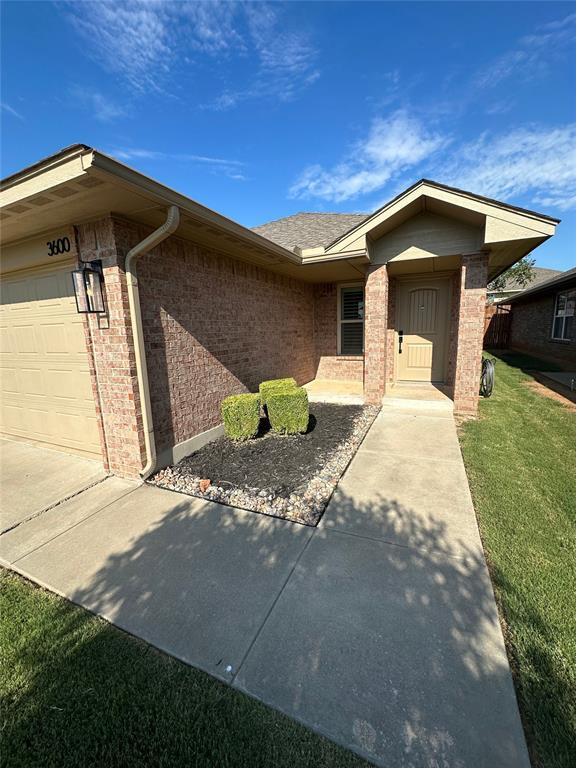 3600 Green Apple Pl, Moore, OK 73160 - property entrance featuring an attached garage, brick siding, a yard, and concrete driveway