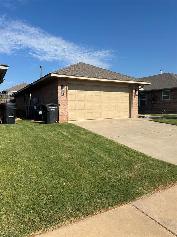 3600 Green Apple Pl, Moore, OK 73160 - view of side of home featuring brick siding, a lawn, and a garage