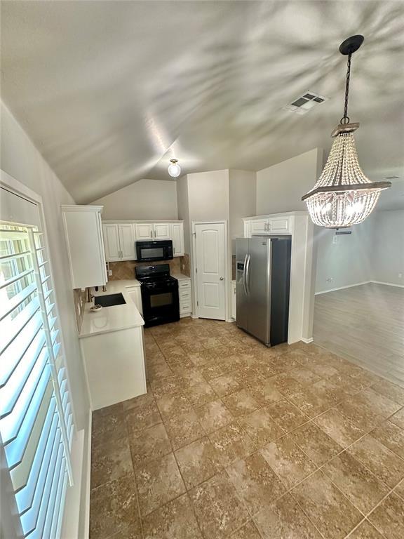 3600 Green Apple Pl, Moore, OK 73160 - kitchen with black appliances, white cabinetry, light countertops, a chandelier, and lofted ceiling