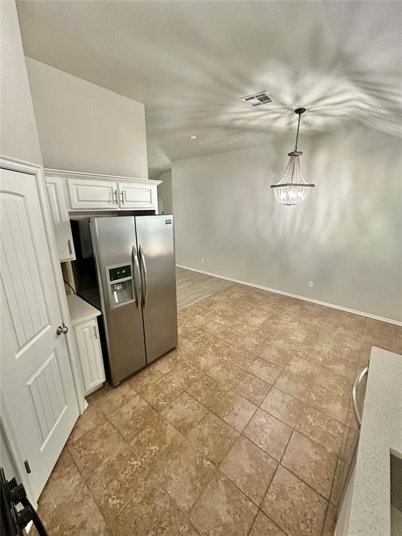 3600 Green Apple Pl, Moore, OK 73160 - kitchen featuring stainless steel fridge with ice dispenser, white cabinets, light countertops, lofted ceiling, and pendant lighting