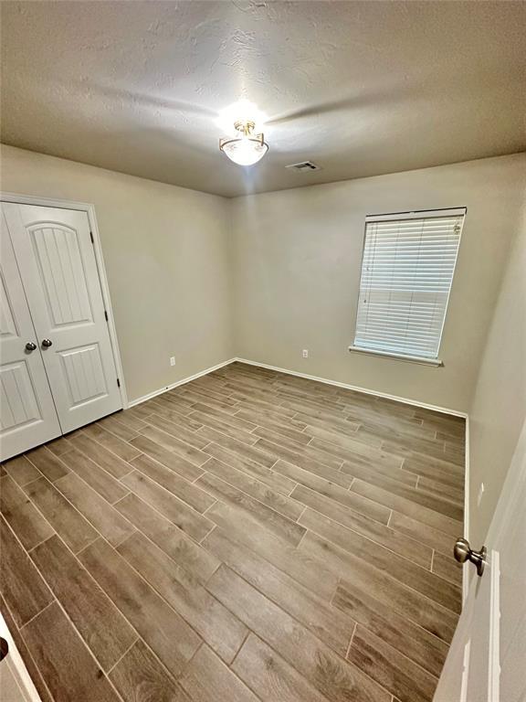 3600 Green Apple Pl, Moore, OK 73160 - empty room featuring wood finished floors and a textured ceiling