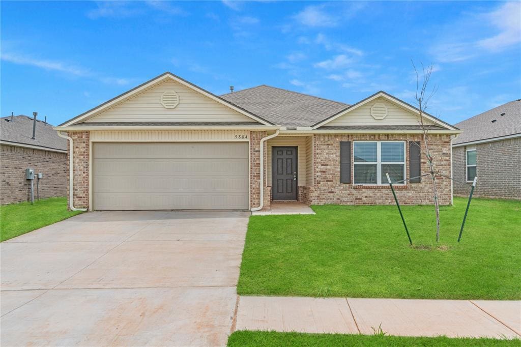 9804 Saddle Dr, Yukon, OK 73099 - ranch-style house with driveway, a front lawn, a garage, and brick siding