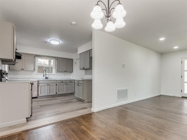 1420 SW 67th St, Oklahoma City, OK 73159 - kitchen featuring gray cabinetry, light wood-style floors, light countertops, a chandelier, and decorative light fixtures