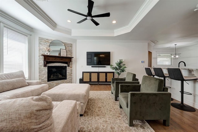 15728 Egerton Pl, Edmond, OK 73013 - living area with ceiling fan, ornamental molding, wood finished floors, a stone fireplace, and a raised ceiling