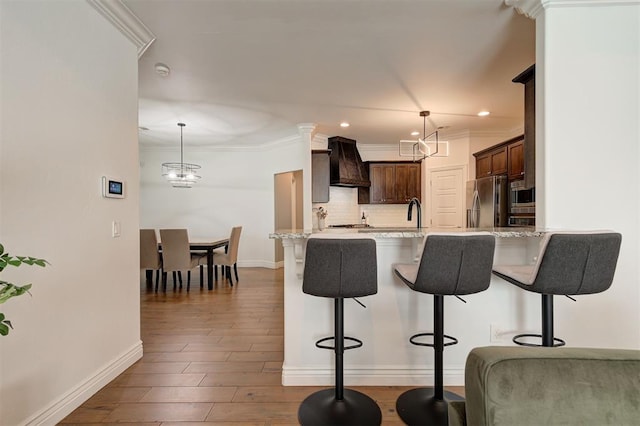 15728 Egerton Pl, Edmond, OK 73013 - kitchen with dark brown cabinetry, a breakfast bar, premium range hood, light stone counters, and a peninsula