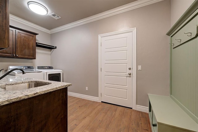 15728 Egerton Pl, Edmond, OK 73013 - laundry room featuring cabinet space, independent washer and dryer, light wood-style flooring, and ornamental molding