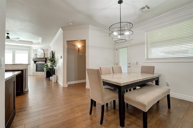 15728 Egerton Pl, Edmond, OK 73013 - dining room featuring ornamental molding, light wood-style floors, a ceiling fan, a chandelier, and a tray ceiling